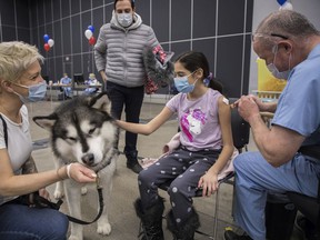 Ella Biasini pets a therapy dog ​​named Zodiak as she receives a COVID-19 vaccine at the Palais des congrès on February 5, 2022.