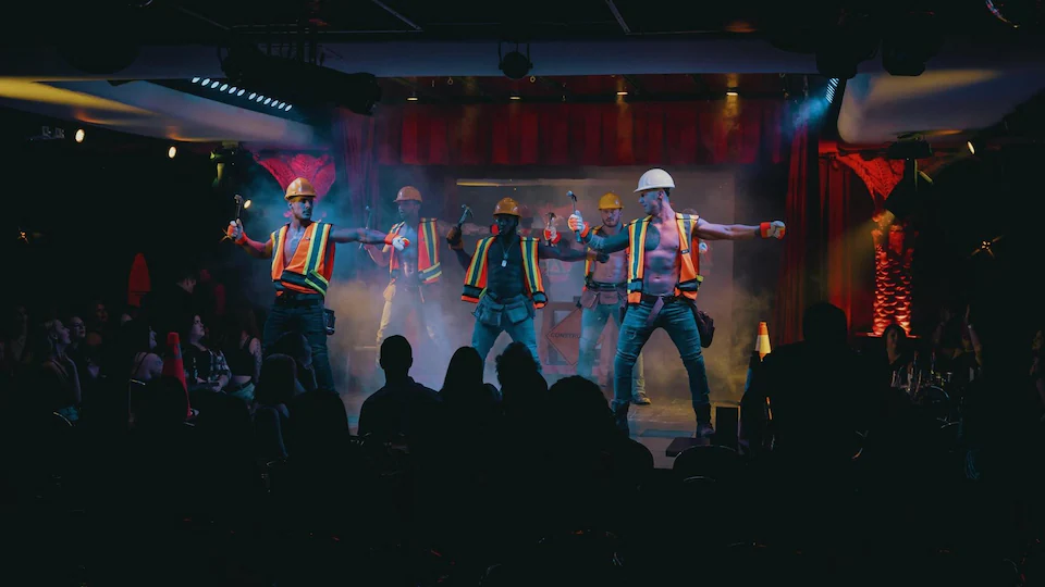 Cinq danseurs sur une scène déguisés en travailleurs de la construction.