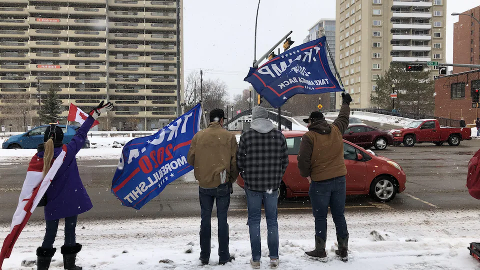 Des gens manifestent près de l'Assemblée législative de l'Alberta en brandissant des drapeaux de l'ancien président américain Donald Trump à Edmonton, le samedi 5 février 2022.