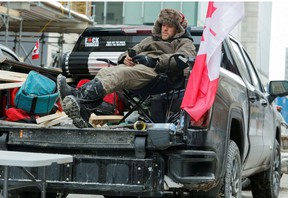 A man relaxes in his pickup truck as truckers and supporters continue their protest in Ottawa on Sunday.