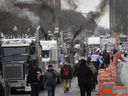 Protesters walk along René-Lévesque Blvd., as trucks race their engines near the National Assembly on the second day of a protest against COVID-19 vaccine and health restrictions held on Sunday, Feb. 6, 2022.  