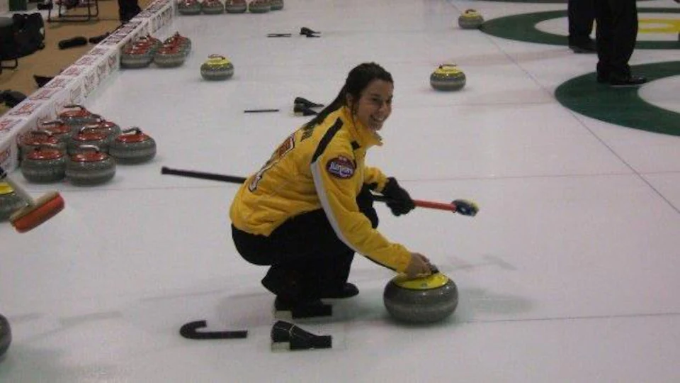 Jeune femme accroupie, avec une pierre de curling.