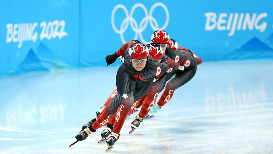 Courtney Sarault et trois autres patineuses canadiennes en plein virage sur la courte piste.