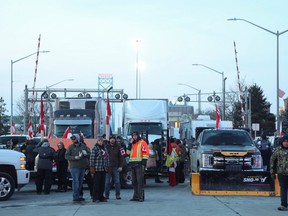 Les gens se tiennent à côté de véhicules bloquant la route menant du pont Ambassador, reliant Detroit et Windsor, le 8 février 2022. REUTERS/Carlos Osorio