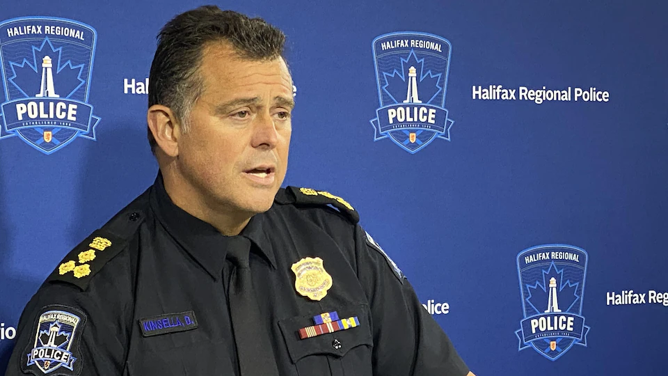 Le chef de police en uniforme devant un mur bleu.