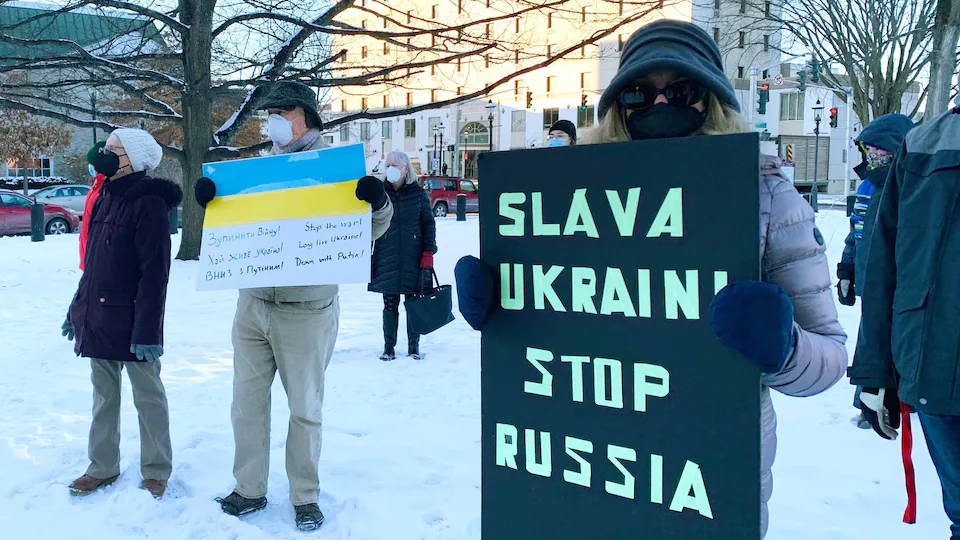 People with placards standing in the snow in a public square.