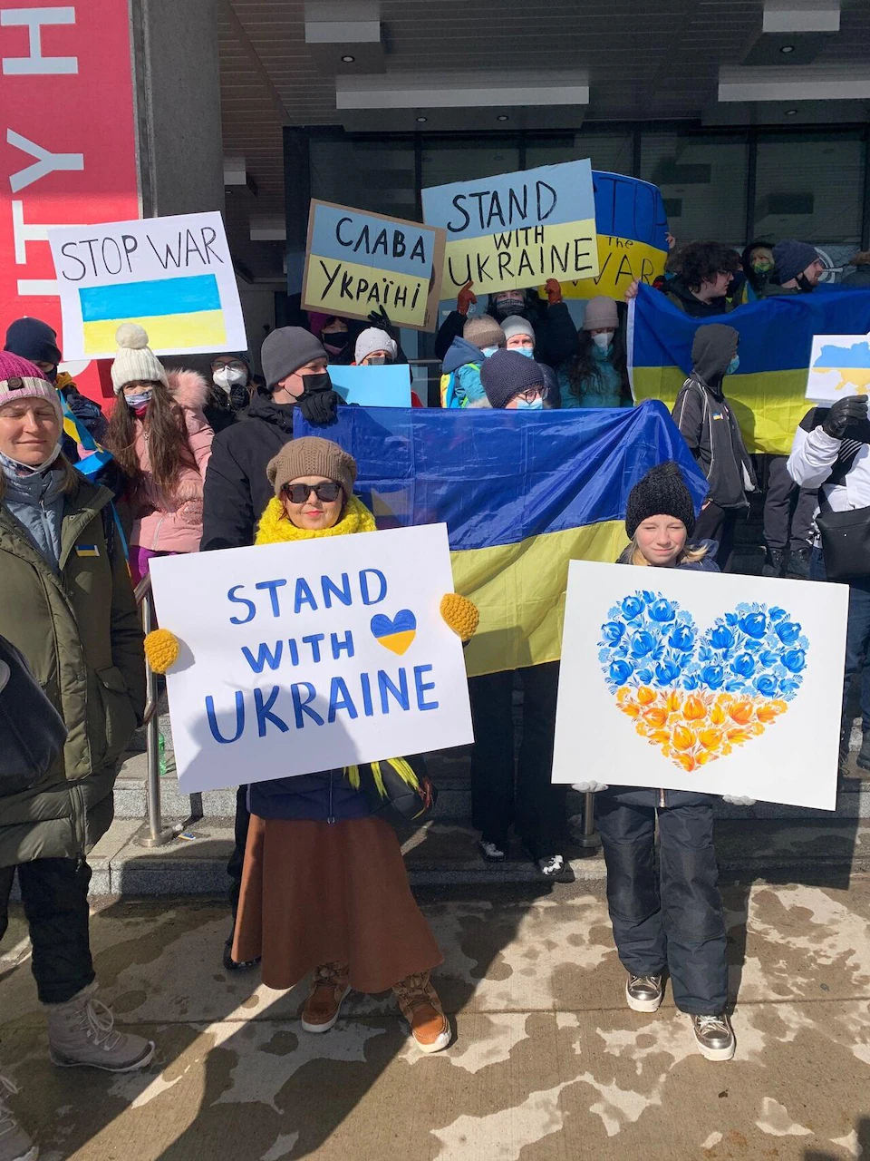 People gathered in a public square with blue and yellow signs, the colors of the Ukrainian flag.