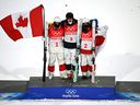 Gold medalist Walter Wallberg of Sweden, center, silver medalist Mikael Kingsbury of Canada, left, and bronze medalist Horishima Ikuma of Japan hold their national flags while standing on the podium.  
