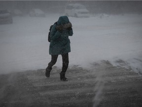 MONTREAL, QUE.: JANUARY 17, 2022 -- A woman tries to shield her face from blowing snow at the corner of Jean Talon and Chateaubriand on Monday January 17, 2022 during the the first winter storm of the year.  (Pierre Obendrauf / MONTREAL GAZETTE) ORG XMIT: 67280 - 9064