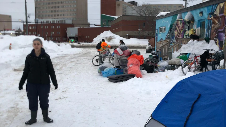 Une personne devant un centre de réchauffement pour sans-abri, à côté d’une tente. 