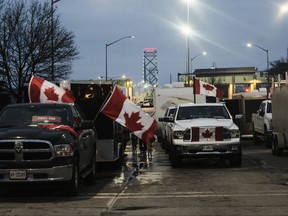 Mercredi, des manifestants avec des camions et d'autres véhicules ornés de pancartes et de drapeaux canadiens se rassemblent sur le pont Ambassador.  Les manifestants ont fermé le pont entre Detroit et Windsor depuis lundi.  Chaque jour de fermeture coûte 450 millions de dollars aux économies du Canada et des États-Unis