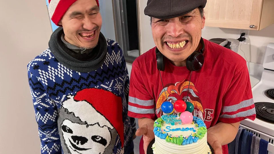 Deux hommes, dont l'un tient un gâteau d'anniversaire.
