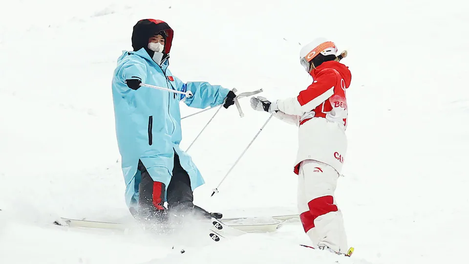 Un préposé remet un bâton de ski à Justine Dufour-Lapointe.
