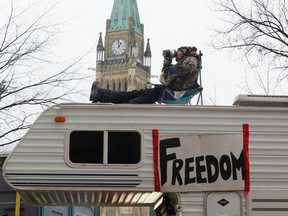 Sur cette photo du 6 février, un homme est assis sur le toit d'une caravane devant la Colline du Parlement pendant le blocus continu des camionneurs du centre-ville d'Ottawa.