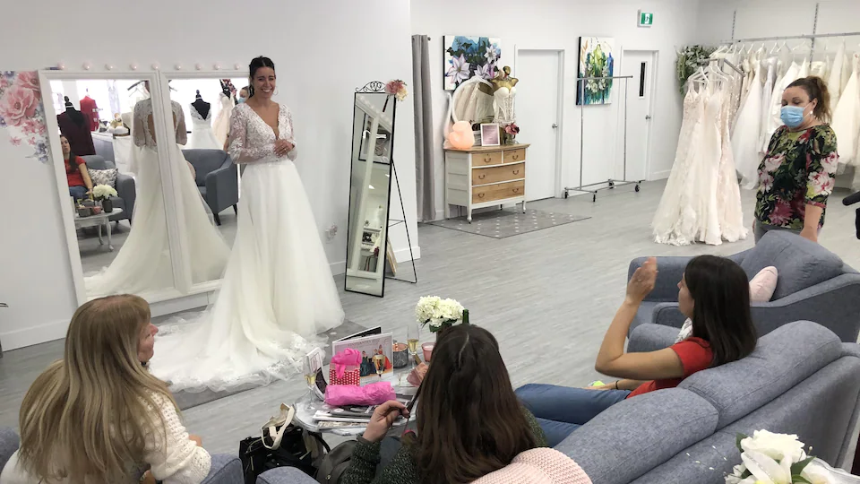 Une fiancée essaie des robes de mariée devant ses amies.