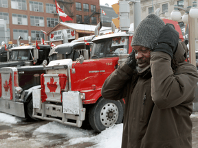File: A man covers his ears while passing honking trucks in Ottawa on Thursday. Lots is known about the health risks of noise, including cardiovascular disease, cognitive impairment, sleep disturbance and mental health impacts.