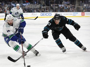 Vancouver Canucks defenseman Kyle Burroughs skates toward the puck as San Jose Sharks left wing Matt Nieto defends during the first period of an NHL hockey game in San Jose, Calif., Thursday, Feb. 17, 2022.