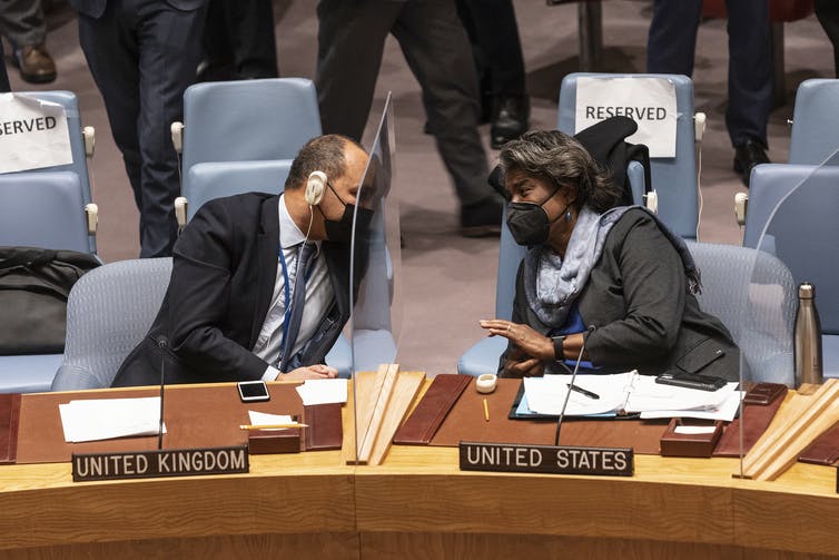 UK Ambassador James Kariuki and US Ambassador Linda Thomas-Greenfield lean towards each other across a table during a UN Security Council meeting on Ukraine on January 21, 2019. 2022. 