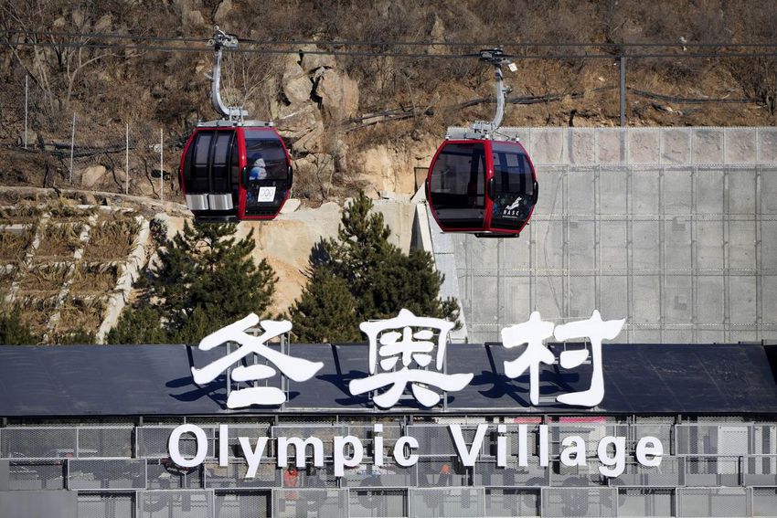 Gondolas glide past a sign for the Olympic Village at the 2022 Winter Olympics, Wednesday, Feb.  2, 2022, in the Yanqing district of Beijing.