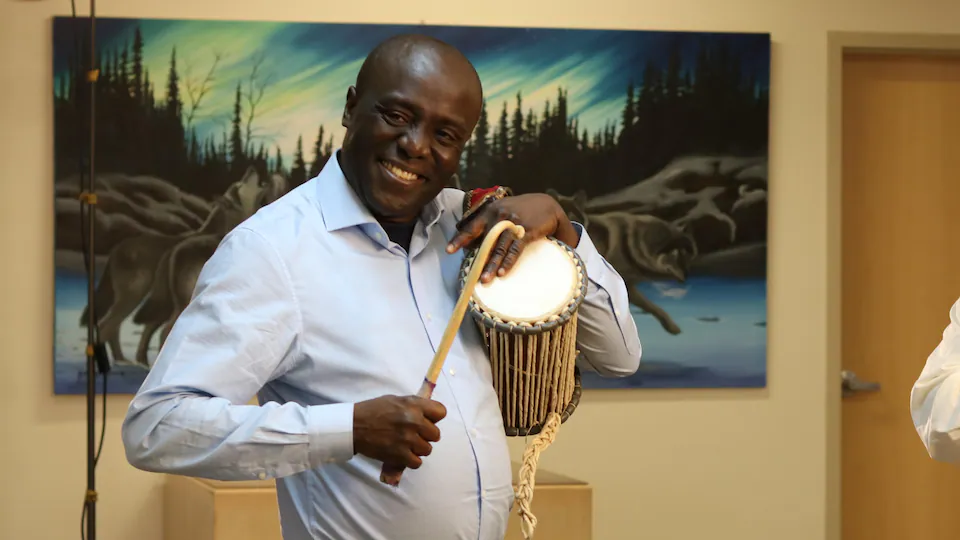Joseph Atoyebi souriant et jouant de son tambour.