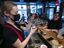 Bartender Maggie Morris pours a pint of beer while sharing some new bar talk with Brigeen O'keefe and Javier Lee at Burgundy Lion restaurant on Monday Jan. 31, 2022.