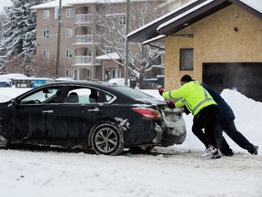 Motorists push their car out of the snow near 106 Street and 87 Avenue in Edmonton, on Friday, March 4, 2022.