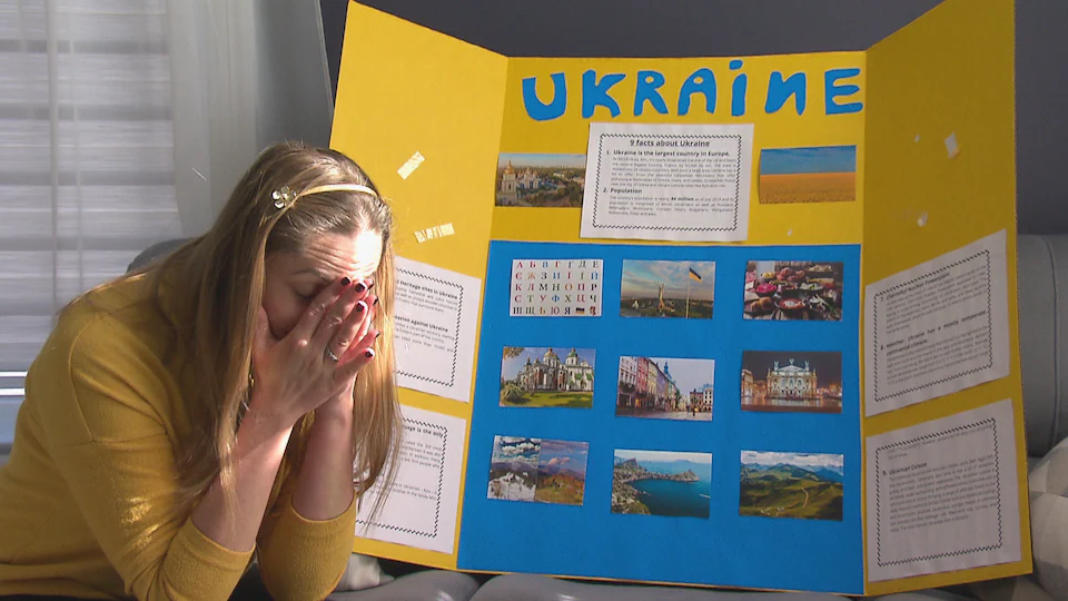 Une femme triste devant une pancarte amateure sur laquelle de nombreuses informations sur l’Ukraine sont écrites. 