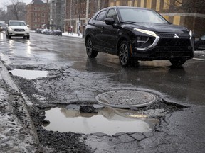 Motorists are forced to drift out of their lane to avoid a series of massive potholes on Sherbrooke St. at the corner of Atwater Ave. in Montreal on Monday, March 7, 2022.