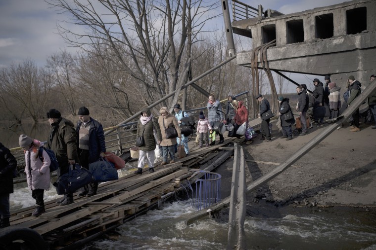 Ukrainians cross an improvised path under a destroyed bridge while fleeing Irpin, on the outskirts of Kyiv, Wednesday.