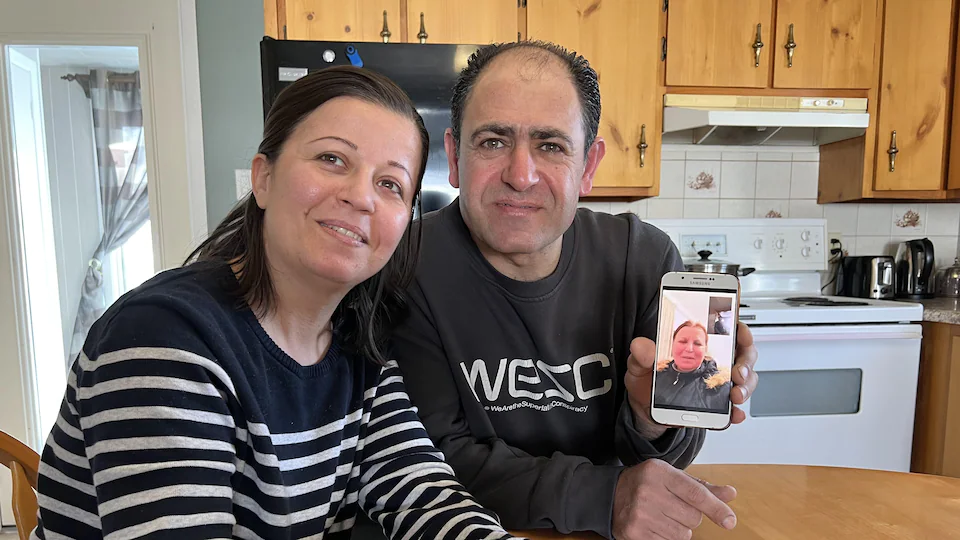 Deux syriens montrent sur leur téléphone la famille avec qui ils sont en communication.