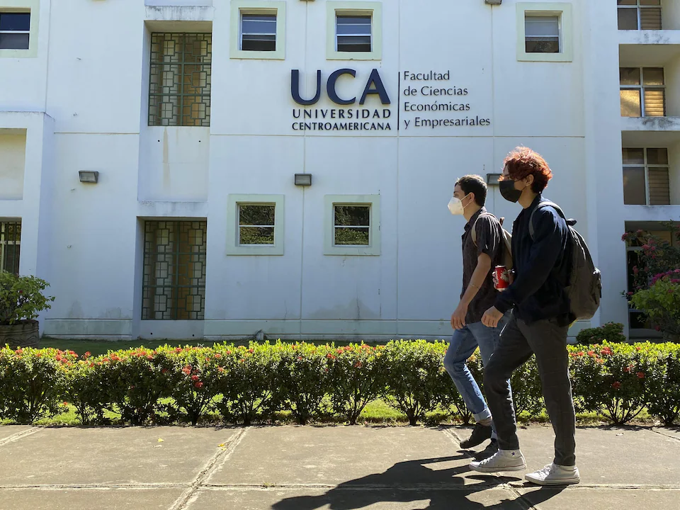 Des étudiants marchent devant un bâtiment.
