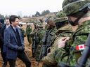 Le premier ministre Justin Trudeau s'entretient avec des troupes de l'OTAN, dont des soldats canadiens, lors d'une visite à la base militaire d'Adazi, au nord-est de Riga, en Lettonie, le 8 mars.