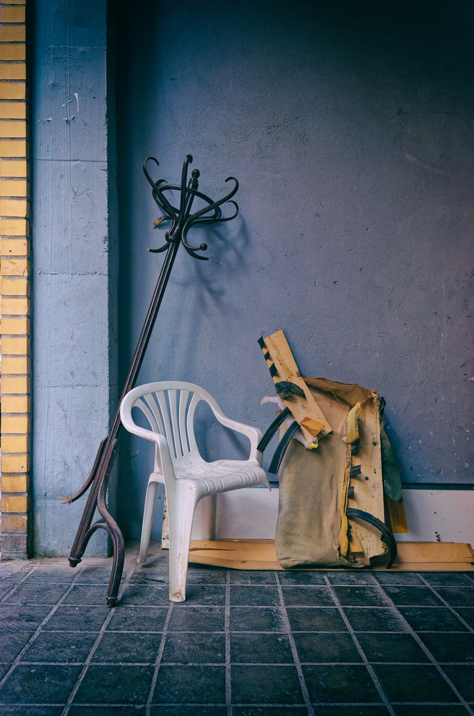 A chair and coat stand leaning against a wall