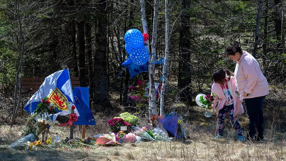 Deux personnes viennent ajouter des ballons et des fleurs près de là où elle est morte.