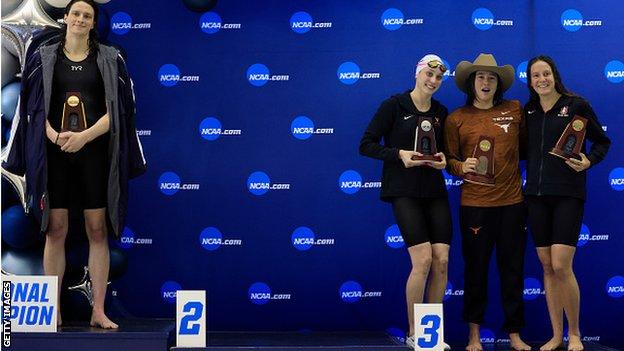 Transgender woman Lia Thomas (L) of the University of Pennsylvania stands on the podium after winning the 500-yard freestyle as other medalists (LR) Emma Weyant, Erica Sullivan and Brooke Forde pose for a photo