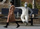 A woman walks past a statue wearing a face mask in Edmonton during the COVID-19 pandemic on April 14, 2021.