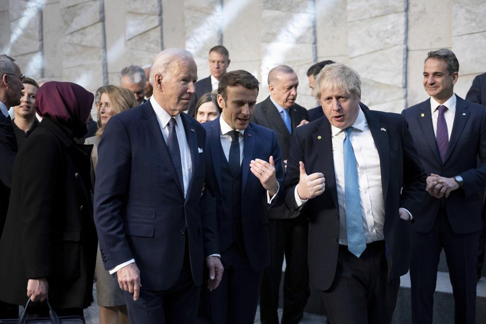 President Joe Biden, left, talks with French President Emmanuel Macron and British Prime Minister Boris Johnson, right, as they arrive at NATO Headquarters in Brussels, Thursday, March 24, 2022.