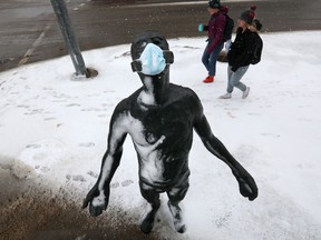 Pedestrians make their way past the sculpture InScope, created by Dam de Nogales, near 87 Avenue and 112 Street, in Edmonton on Sunday March 20, 2022. A COVID-19 face mask is visible on the sculpture.