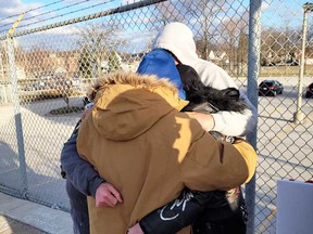 Loved ones of Kenny McEldowney of Windsor embrace each other for support after placing a memorial where he died on Wyandotte Street West due to a collision.  Photographed March 27, 2022. Image courtesy of the McEldowney family.