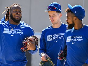 Toronto Blue Jays' Vladimir Guerrero Jr., left, Cavan Biggio, center, and Teoscar Hernandez chat as they walk to a practice field during a spring training workout, Sunday, March 13, 2022, in Dunedin, Fla.