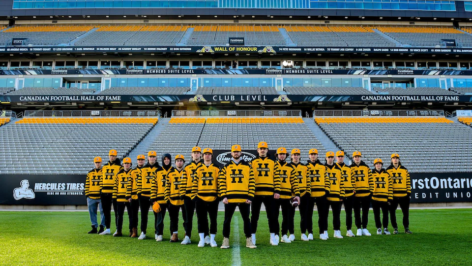 Les joueurs des Bulldogs posent pour une photo d'équipe. Ils sont tous vêtus d'un chandail noir et or décoré de la lettre H au centre.