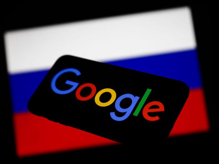 Google au téléphone devant le fond du drapeau de la Russie