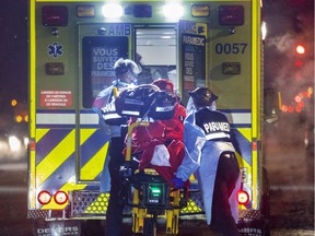 MONTREAL, QUE.: January 12, 2022 -- Paramedics wheel a COVID patient to an ambulance in Montreal Wednesday January 12, 2022. (John Mahoney / MONTREAL GAZETTE) ORG XMIT: 51318 - 4254