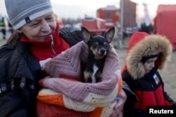 Une femme réagit en tenant un chien alors que des réfugiés ukrainiens traversent la frontière ukraino-slovaque après l'invasion de l'Ukraine par la Russie, à Vysne Nemecke, en Slovaquie, le 3 mars 2022. (Lukasz Glowala/Reuters)