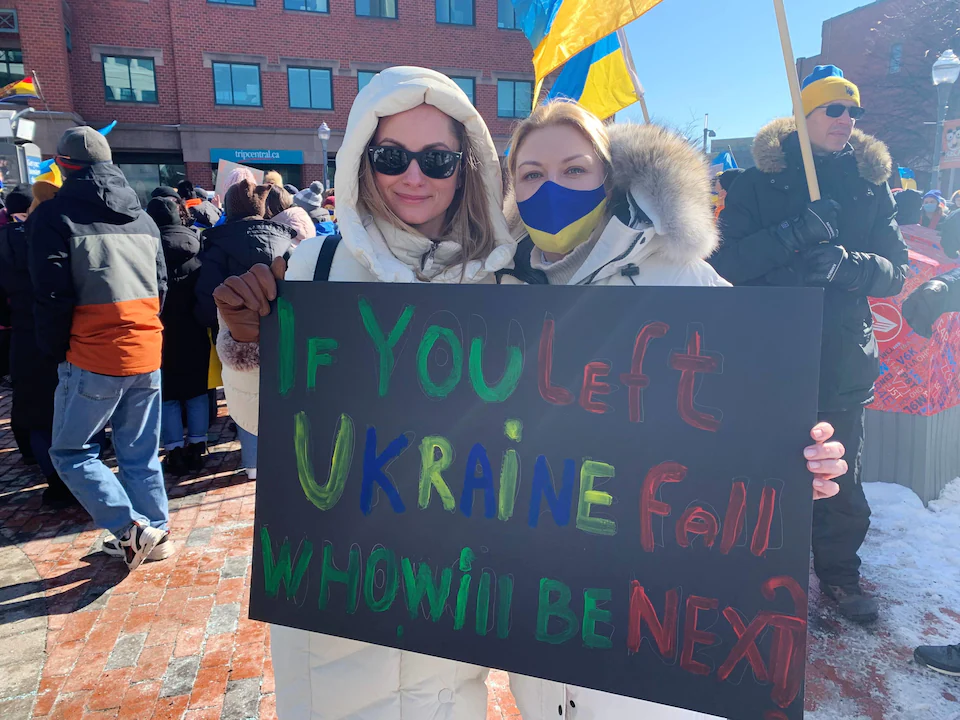 Deux femmes à une manifestation de soutien à l'Ukraine. Elles tiennent une affiche sur laquelle est écrit, en anglais: « If you left (sic) Ukraine fall, who will be next?»