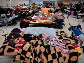 A mother sleeps with her children among many others in a temporary shelter hosting the Ukrainian refugees located in a former shopping center near the city of Przemysl, on March 8, 2022.