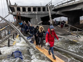 Residents of Irpin flee heavy fighting via a destroyed bridge as Russian forces entered the city on March 7, 2022 in Irpin, Ukraine.