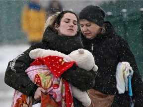 A woman carries an infant as they cross the border into Poland from Ukraine at the border crossing in Medyka, eastern Poland, on March 9, 2022.