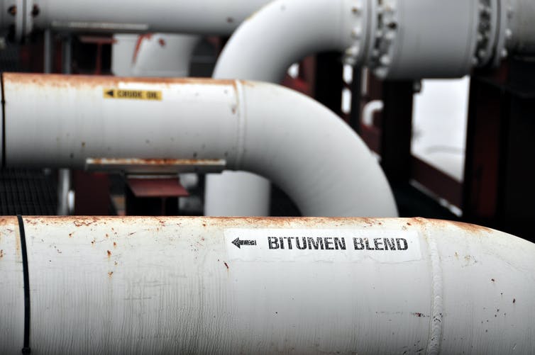 Close up of curved pipes with one labeled Bitumen Blend.