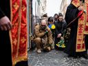 People kneel during the funeral ceremony of Yuriy Dadak-Ruf and Taras Kryt, killed due to artillery shelling in the Luhansk region, in Lviv, Ukraine, April 9, 2022